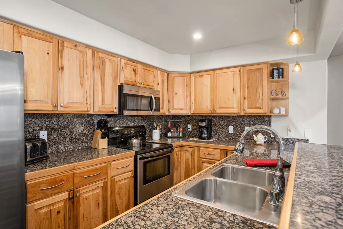 A spacious kitchen with a central island, granite countertops, stainless steel appliances, and warm wooden cabinetry. The setting is ideal for meal preparation, entertaining, and group activities, with ample workspace and an inviting layout.