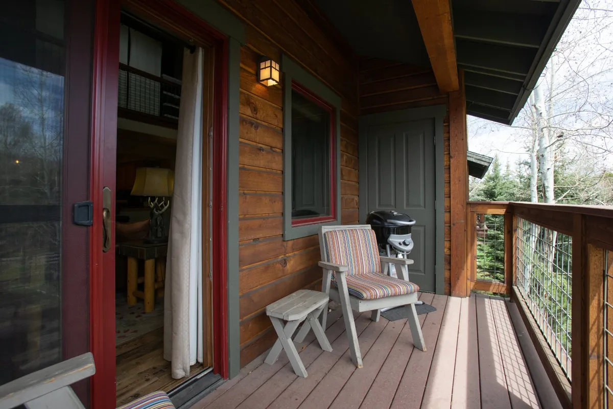 An inviting deck scene with comfortable chairs, a grill, and a wooden railing, all set against a backdrop of nature. The scene hints at après ski relaxation, social gatherings, and enjoying the outdoor surroundings after a day of adventure.
