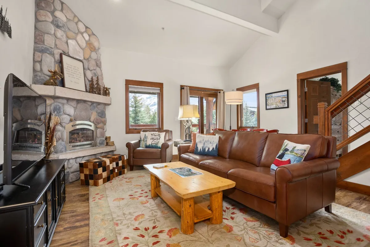 A cozy living room with a stone fireplace, leather sofa, and wooden coffee table. The atmosphere is warm and comfortable, encouraging relaxation and socializing after a day spent downtown.